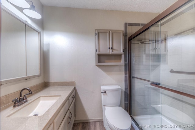 bathroom featuring vanity, toilet, a shower with door, and a textured ceiling