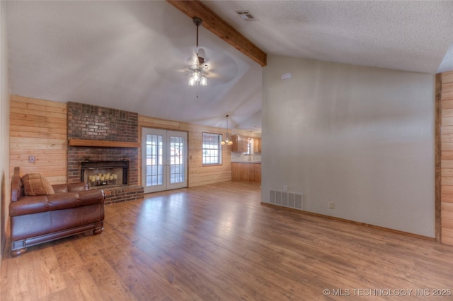 unfurnished living room with beam ceiling, hardwood / wood-style flooring, french doors, and a textured ceiling