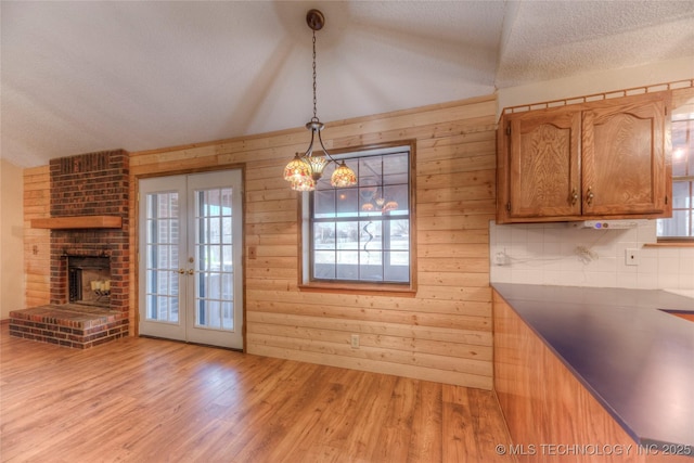 kitchen with wooden walls, decorative light fixtures, light hardwood / wood-style floors, a textured ceiling, and french doors