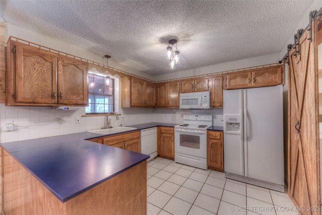 kitchen featuring sink, white appliances, hanging light fixtures, kitchen peninsula, and a barn door