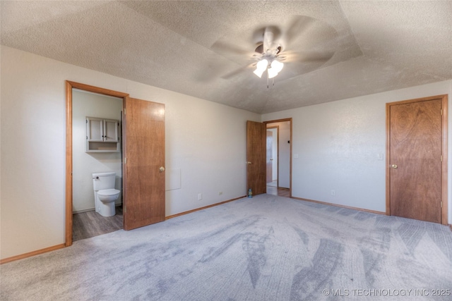 unfurnished bedroom featuring ceiling fan, ensuite bathroom, a textured ceiling, and carpet