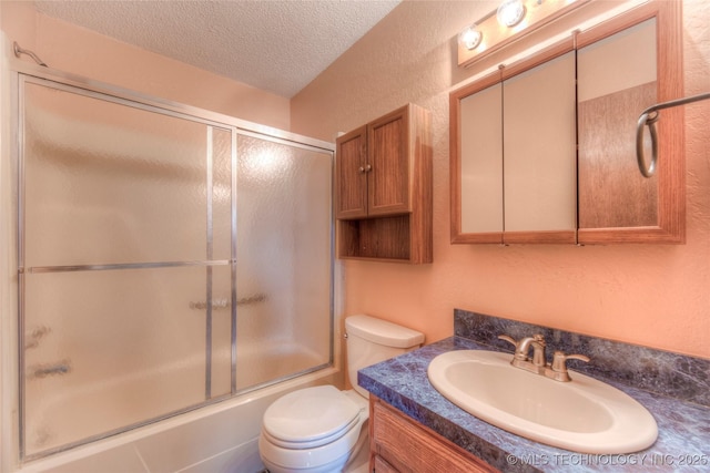 full bathroom featuring vanity, bath / shower combo with glass door, toilet, and a textured ceiling