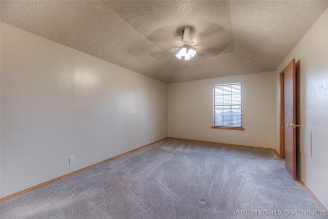 empty room with ceiling fan, lofted ceiling, carpet floors, and a textured ceiling