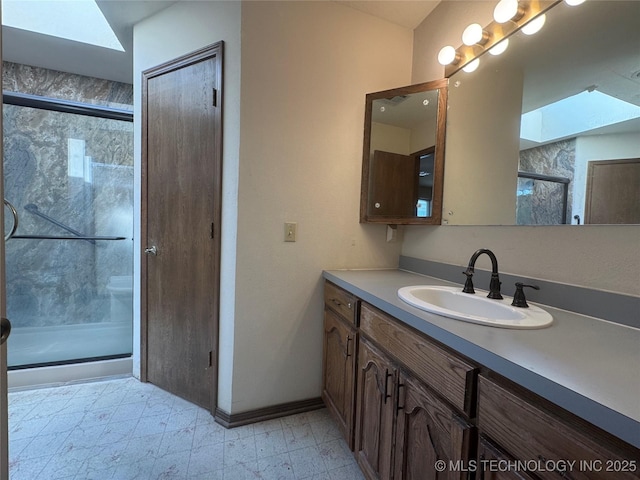 bathroom featuring a skylight, vanity, and an enclosed shower