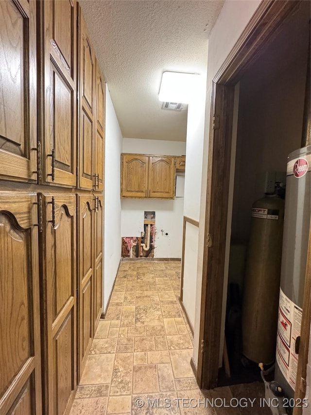 hallway with water heater and a textured ceiling