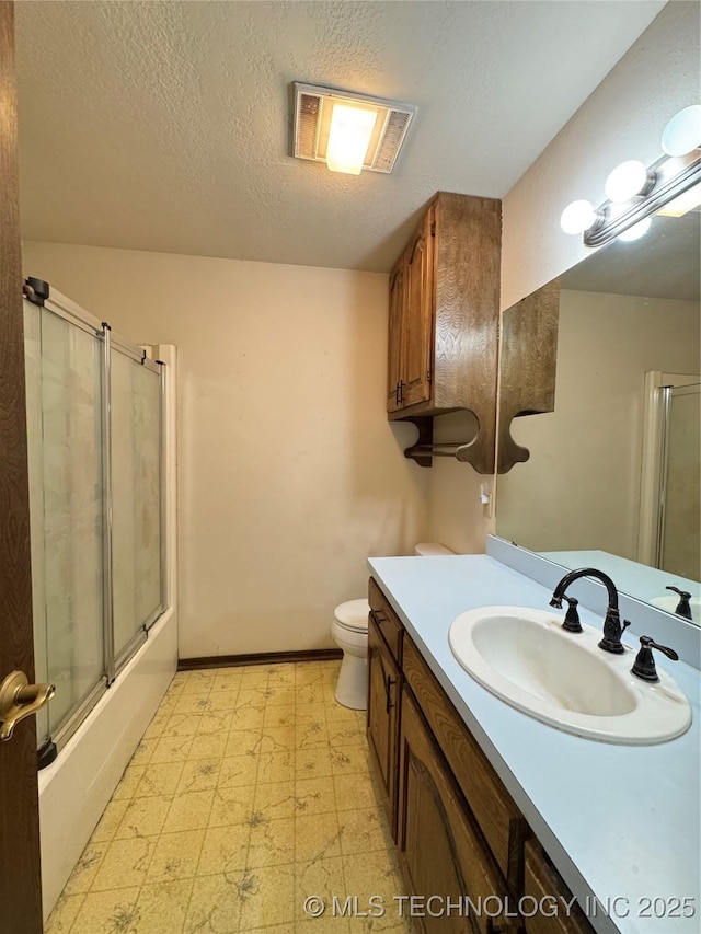 full bathroom featuring vanity, a textured ceiling, toilet, and combined bath / shower with glass door