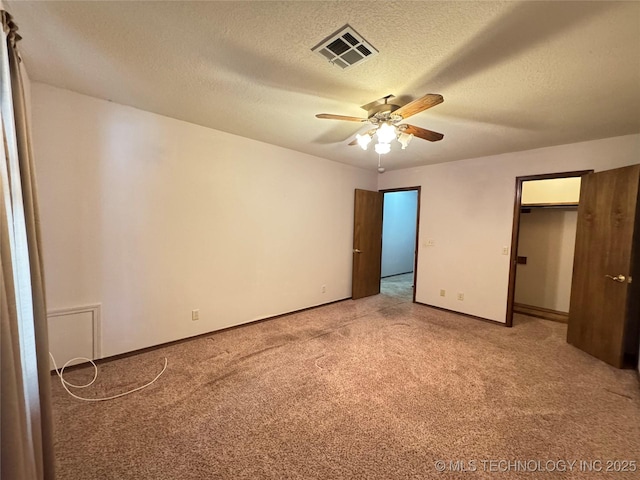 unfurnished bedroom with ceiling fan, light colored carpet, and a textured ceiling