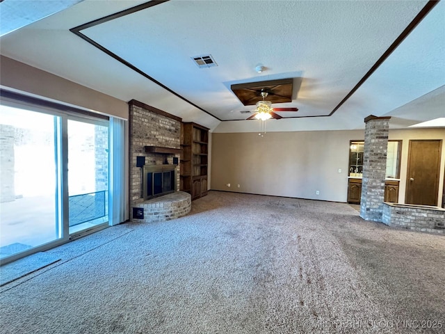 unfurnished living room with ornate columns, carpet floors, ceiling fan, a brick fireplace, and a textured ceiling