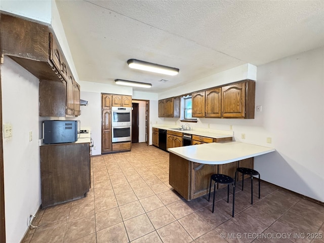 kitchen with sink, a kitchen breakfast bar, black dishwasher, kitchen peninsula, and double oven