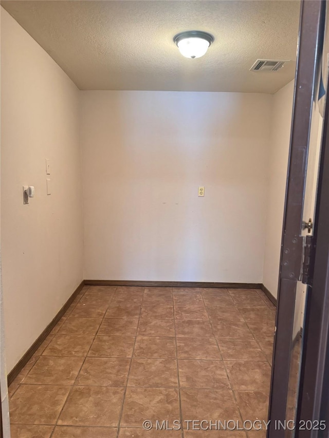 tiled empty room featuring a textured ceiling