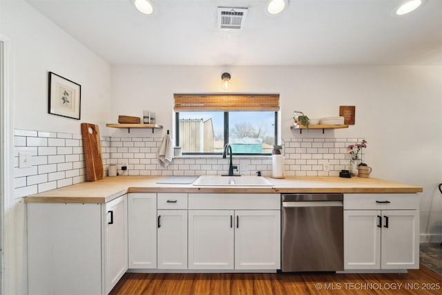 kitchen with butcher block countertops, sink, white cabinetry, backsplash, and stainless steel dishwasher