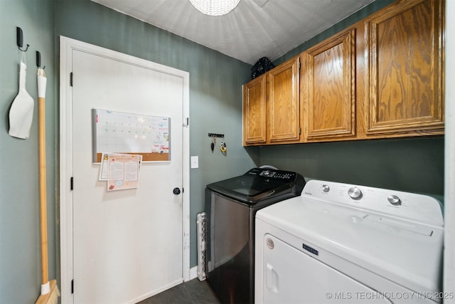 clothes washing area featuring cabinets and separate washer and dryer