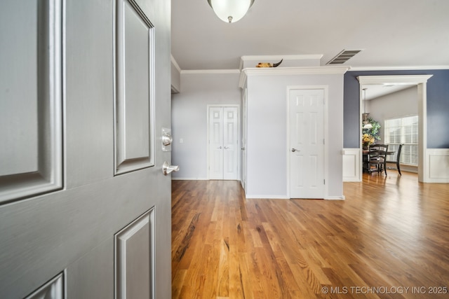 interior space featuring wood finished floors, visible vents, and ornamental molding