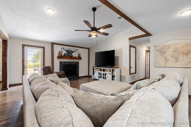 living room with ceiling fan, a large fireplace, dark hardwood / wood-style flooring, and lofted ceiling with beams