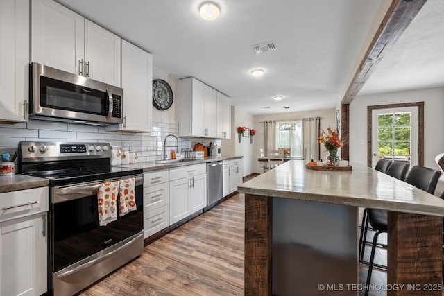 kitchen featuring appliances with stainless steel finishes, a center island, a breakfast bar area, and white cabinets