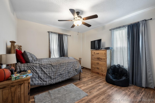 bedroom featuring ceiling fan, dark hardwood / wood-style floors, and a textured ceiling