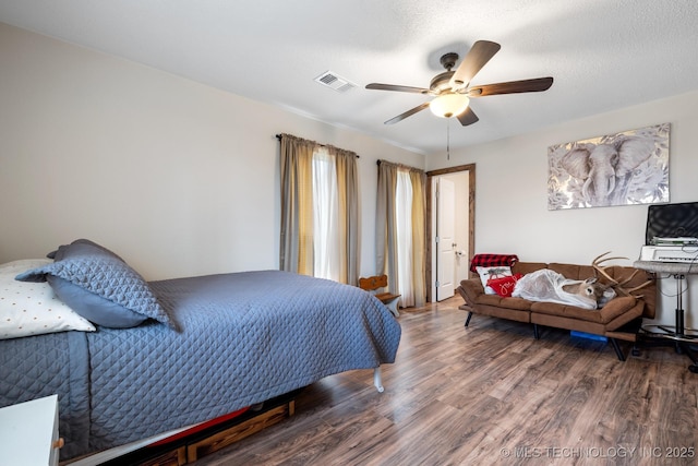 bedroom with a textured ceiling, wood-type flooring, and ceiling fan