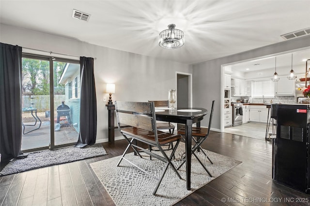 dining space featuring a notable chandelier, sink, and dark wood-type flooring