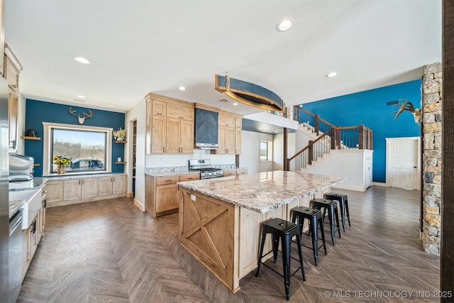 kitchen with a large island, light brown cabinetry, appliances with stainless steel finishes, a breakfast bar, and recessed lighting