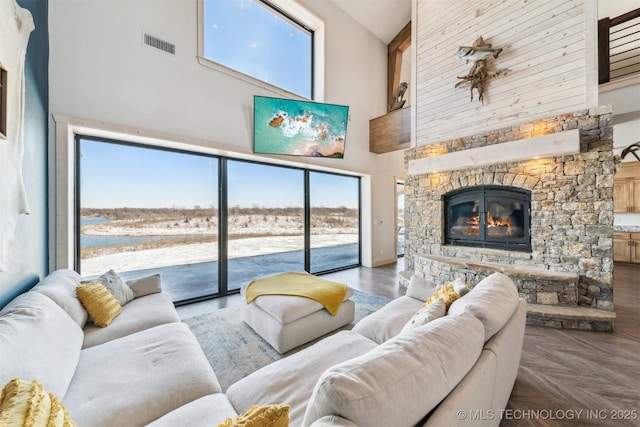 living room featuring visible vents, a towering ceiling, and a stone fireplace