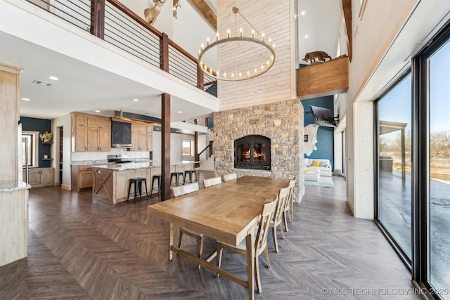9501 S 4170th Rd, Claremore, OK 74017 - dining room featuring healthy amount of natural light, a high ceiling, a fireplace, a chandelier, and baseboards
