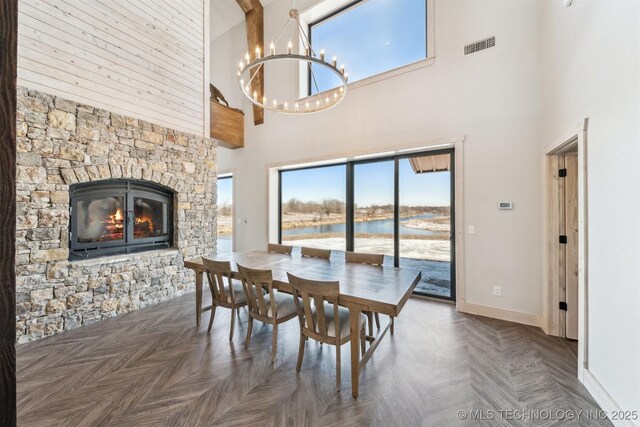9501 S 4170th Rd, Claremore, OK 74017 - dining space with a high ceiling, a chandelier, baseboards, a stone fireplace, and a water view