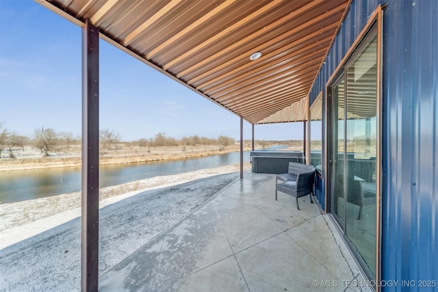 view of patio with a hot tub and a water view