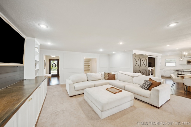 living room featuring washer / clothes dryer, built in features, and a barn door