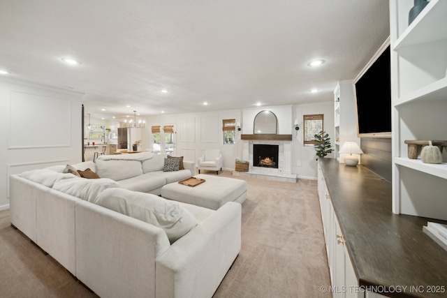 living room featuring an inviting chandelier, a large fireplace, light colored carpet, and a wealth of natural light