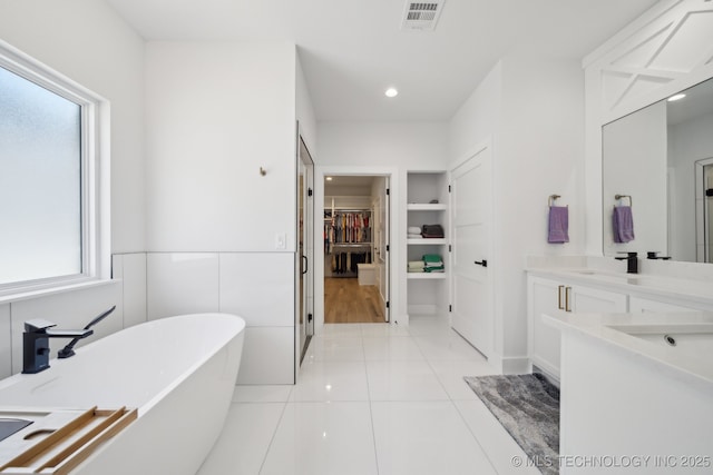 1105 W 86th St, Tulsa, OK 74132 - full bath featuring a soaking tub, a spacious closet, vanity, tile patterned flooring, and recessed lighting