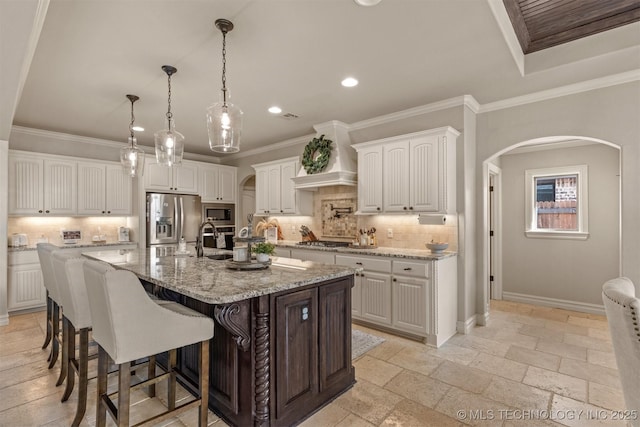 kitchen featuring a kitchen island with sink, light stone counters, stainless steel appliances, and white cabinets