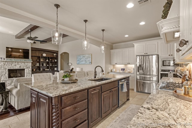 kitchen featuring stainless steel appliances, white cabinetry, an island with sink, and dark brown cabinetry