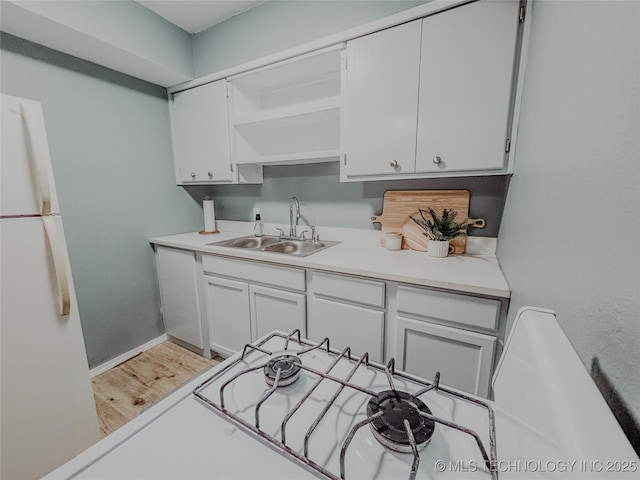 kitchen featuring white fridge, sink, white cabinets, and light wood-type flooring