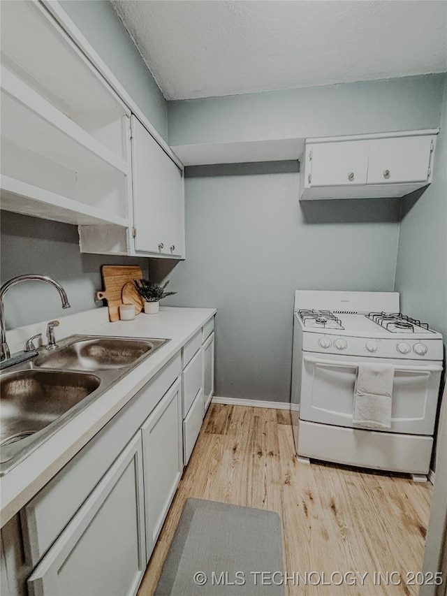 kitchen featuring sink, white range with gas stovetop, white cabinets, and light hardwood / wood-style floors