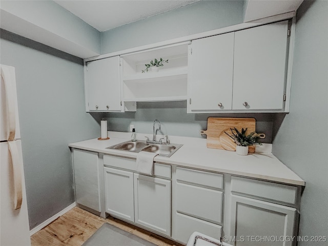 kitchen featuring white fridge, sink, white cabinets, and light hardwood / wood-style floors