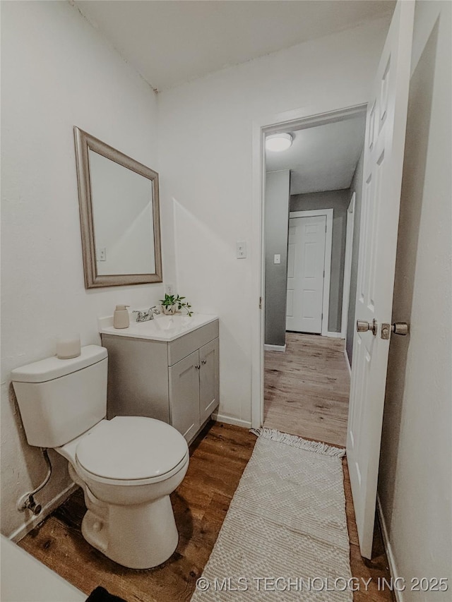 bathroom with vanity, toilet, and hardwood / wood-style floors