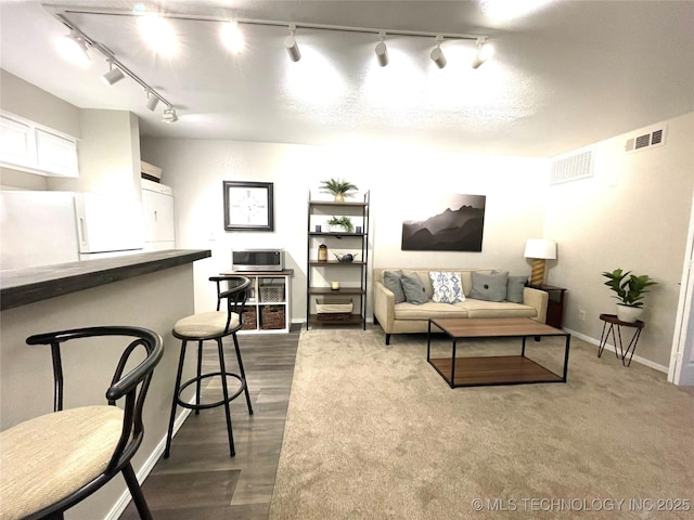 living area featuring track lighting, baseboards, dark wood-style floors, and visible vents