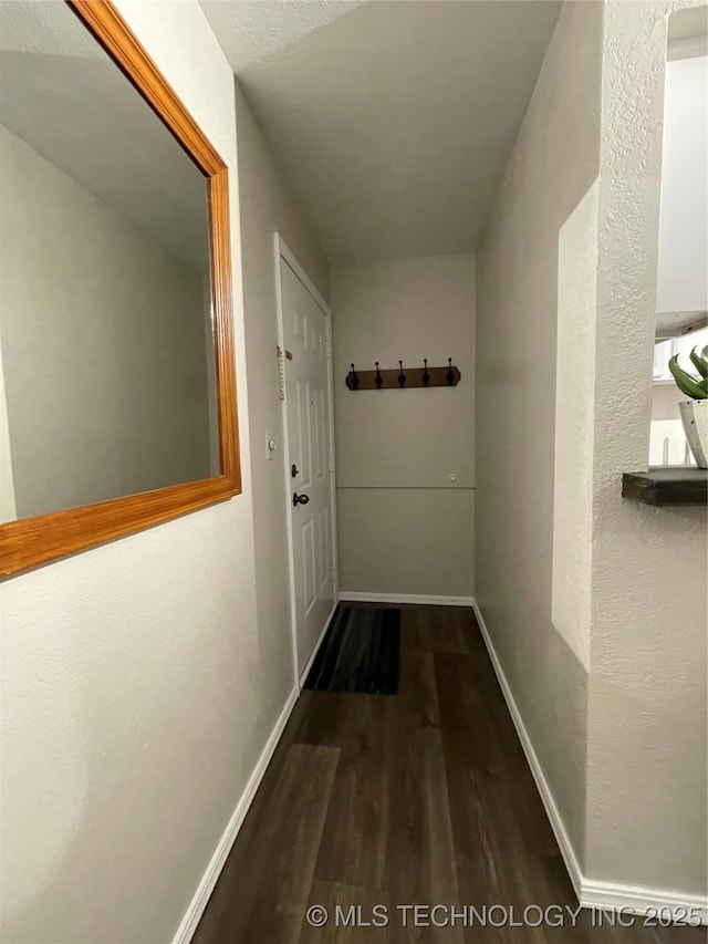 corridor featuring baseboards and wood finished floors