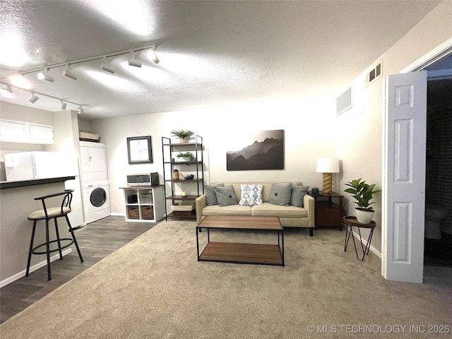 6663 S Victor Ave Unit H # 305, Tulsa, OK 74136 - living area with estacked washer and dryer, rail lighting, dark colored carpet, and a textured ceiling