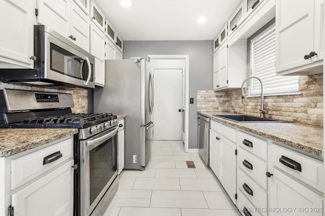 kitchen with appliances with stainless steel finishes, sink, white cabinets, and light stone counters