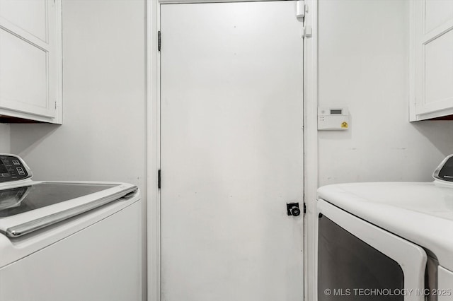 clothes washing area featuring cabinets and washer and clothes dryer