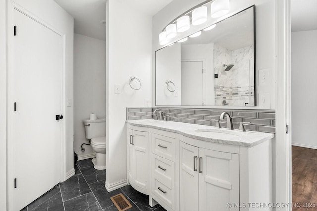 bathroom featuring vanity, a shower, backsplash, and toilet