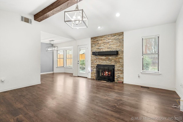 unfurnished living room featuring a notable chandelier, a stone fireplace, dark wood-type flooring, and lofted ceiling with beams