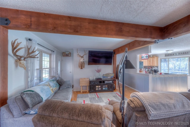 living room with a textured ceiling, light wood-type flooring, and beam ceiling