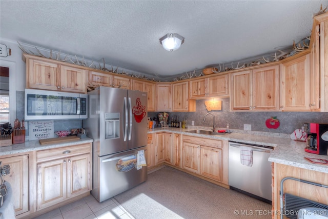 kitchen featuring stainless steel appliances, a sink, a textured ceiling, and light stone countertops