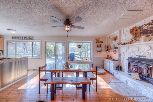 dining room featuring light wood finished floors, a textured ceiling, visible vents, and a ceiling fan