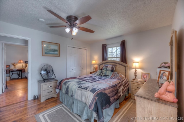 bedroom with a textured ceiling, a closet, light wood-type flooring, and a ceiling fan