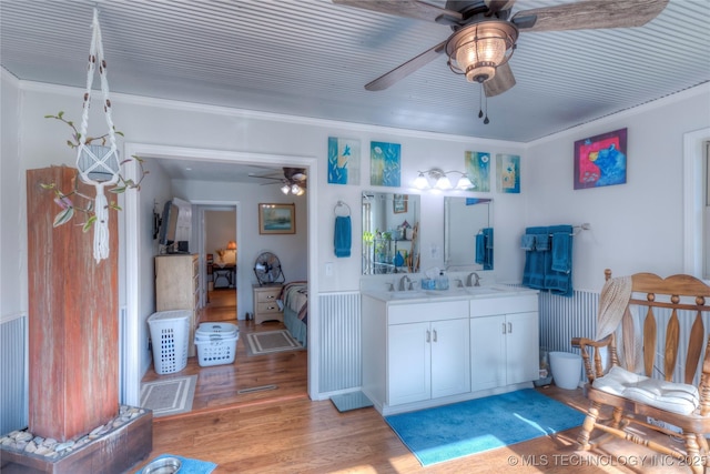 bathroom featuring ensuite bath, ceiling fan, ornamental molding, wood finished floors, and vanity