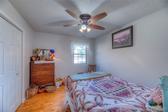 bedroom featuring a textured ceiling, ceiling fan, a closet, and wood finished floors