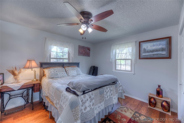 bedroom with light wood-style floors, multiple windows, and a textured ceiling